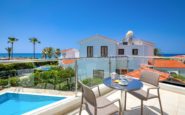 Luxury balcony overlooking pool, ocean, and Mediterranean-style Paphos Villa in residential neighbourhood.