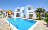 Modern two-story Paphos villa with swimming pool, garden, and palm tree under clear blue sky.