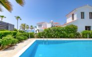 Luxurious poolside retreat in Mediterranean resort with clear blue skies and lush greenery.