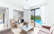 Modern living room with bright, airy atmosphere, plush sofas, glass coffee table, and pool view.