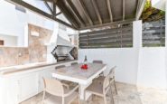 Inviting outdoor dining area with modern furniture, barbecue grill, and wooden pergola.