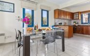 Kissonerga Villa with Contemporary kitchen-dining area blending modern and rustic elements, featuring glass table with fruit.