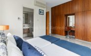 Kissonerga Villa with Modern twin bedroom with blue accents, en suite bathroom, wooden wardrobe, and cozy decor.