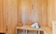 sauna room with wooden bench, towels, ladle, and stove for a relaxing experience.