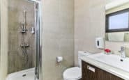 villa for rent with Modern minimalist bathroom with shower, toilet, sink, and natural light for a bright space.