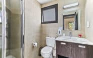 Modern and sleek bathroom with glass shower, white toilet, vanity unit, and minimalist design.