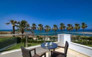 Luxurious villas to rent in Cyprus balcony overlooking tranquil beachfront garden and ocean on a sunny day.