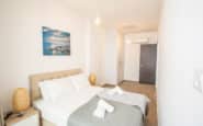 Modern minimalist bedroom with bright atmosphere, beige bed, and serene seaside artwork in holiday rentals in Cyprus Protaras