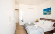 Modern, minimalist bedroom with double bed, coastal art, and wardrobe in Villa Opal, holiday rentals in Cyprus Protaras