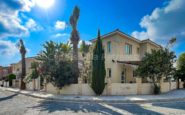 Modern two-story villa with lush garden and palm trees on a sunny corner lot in Kato Paphos