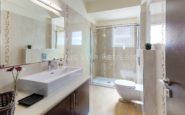 Modern and sleek bathroom with white sink, chrome fixtures, shower area, and practical design.