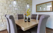 Kato Paphos Villa with Modern dining room with elegant stone table, grey chairs, yellow orchid arrangement, and warm lighting.