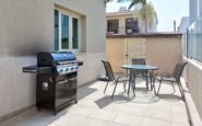 Modern barbecue grill and seating area on outdoor patio between buildings.