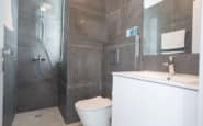 villas in Cyptrus Protaras with Modern and sleek bathroom design with dark grey tiles, shower, toilet, and vanity unit.