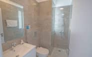 Cyprus Villa Rentals with Modern, elegant compact bathroom with light grey tiles, sleek fixtures, and glass shower enclosure.