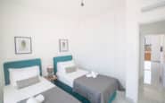 Cyprus Villa Rentals with Bright and inviting bedroom with teal headboards, botanical artworks, and ample storage space.