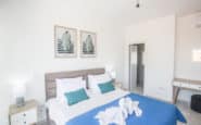 Modern, minimalist bedroom with white decor, double bed, and botanical art in Cyprus Villa Rentals