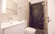 Modern minimalist bathroom with white vanity, chrome fixtures, and contrasting shower area in Cyprus villa.