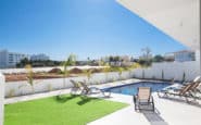 Modern luxury outdoor patio with swimming pool and sun loungers in a coastal residential setting.