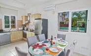 Modern kitchen and dining area with glass-top table and outdoor view.