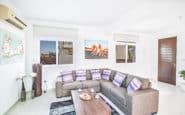 Modern and stylish living room with grey sofa, striped cushions, and colourful artwork.