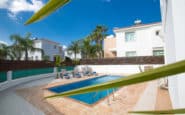 Luxurious private villa rental with pool, palm trees, and modern houses in Protaras, Cyprus.