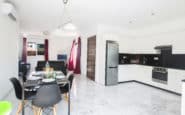 Modern white kitchen and dining area in luxury villa with sleek black accents ideal for Villa hire Cyprus.