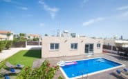 Modern backyard with pool, lounge chairs, and building in a Villa hire Cyprus.