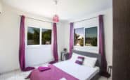 Modern bedroom with purple accents, natural light, and stylish decor in Villa hire Cyprus.