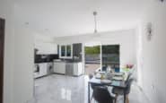 Modern kitchen and dining area with sleek design, natural light, and outdoor view in Villa hire Cyprus.