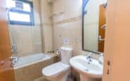 Neat and modern beige bathroom with bathtub, toilet, and sink.