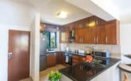 Modern kitchen with dark wooden cabinets, granite island, stainless steel appliances, and natural light.