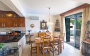 Modern and cozy dining area with kitchen, wooden table, and patio doors in Protaras holiday rentals.