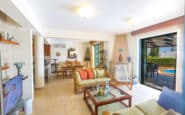 Bright and airy living space with wicker sofa, dining area, and outdoor pool view.