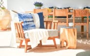 Cozy outdoor seating area with wooden armchair, side table, and dining set under sunlight.