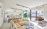 Modern open-plan living space with bright decor, kitchen, dining area, and outdoor terrace in Cyprus Ayia Napa