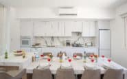 Ayia Napa Villa with Modern white kitchen and dining area with elegant decor and table setting.