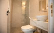 Modern beige tile bathroom with sleek fixtures, glass shower, and minimalist design.