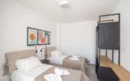 Modern Ayia Napa Villa with twin bedroom with elegant decor, abstract art, and functional wardrobe unit.