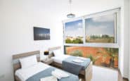 Tripingo Villas in Protaras Cyprus with modern twin bedroom, light blue bedding, contemporary design, and scenic view.