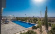 Protaras luxurious pool area with clear blue water, greenery, and bright sunshine for relaxation.