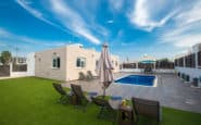 Modern swimming pool oasis with lounge chairs and lush lawn in Protaras, Cyprus.