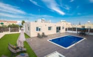 Modern backyard oasis with pristine pool, sunbeds, umbrella, and green grass in Villas in Protaras.