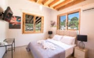 Cozy modern bedroom with rustic beams, white walls, double bed, and stylish decor offered by Villa Rentals in Protaras.