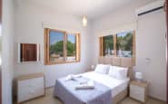 Modern minimalist double bedroom with beige bed, nightstands, and AC in Villa Rentals in Protaras, Cyprus.