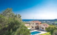 Luxurious modern Villa Rentals in Protaras with pool, surrounded by lush greenery and ocean views.