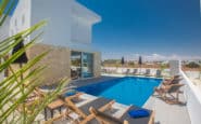 Protaras Holiday Rentals offering modern luxury poolside oasis with sleek design, wooden loungers, and panoramic views.