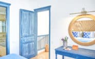 Coastal-themed room with blue door, lavender flowers, and wicker mirror in villas in Cyprus.