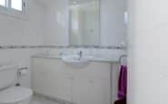 Modern white bathroom with sink, mirror, toilet, and purple towel in this Cyprus Villa for Rent