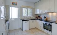 Modern Cyprus Villa for Rent, white kitchen with granite countertop, stainless steel appliances, and vibrant tile accent.